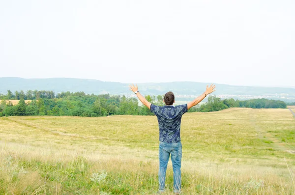 Trendy teenager worship in nature with hands raised to the sky