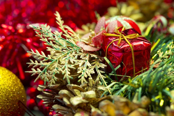 Christmas present ornament on red tinsel and green pin leaves