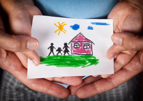 Child and his mom holding a drawn house with family