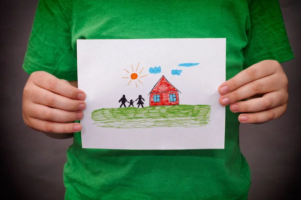 Child holds a drawn house with family