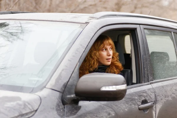 Young woman looks back through the car window