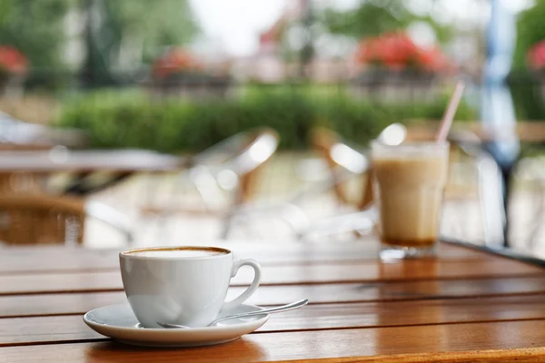 Cup of cappuccino on wooden table in a street coffee shop