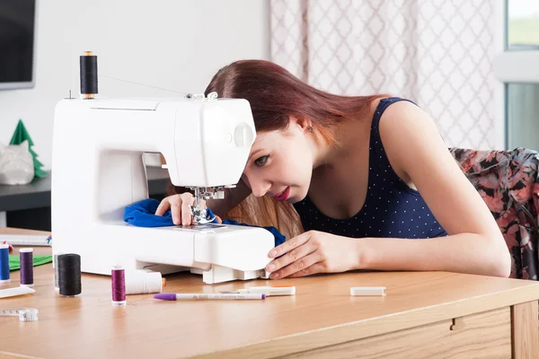 Young woman sewing fabric