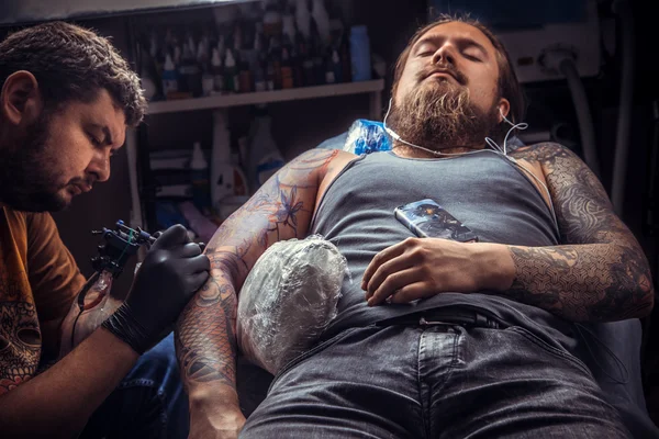 Tattooer doing tattoo in tattoo parlor