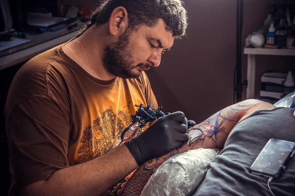 Tattooer doing tattoo in tattoo parlor