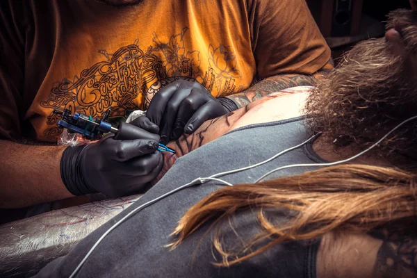Tattoo master working tattooing in tattoo parlour