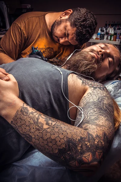 Professional tattoo artist showing process of making a tattoo in tattoo parlour