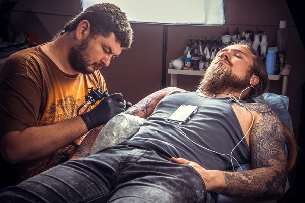 Tattooer making a tattoo in tattoo studio