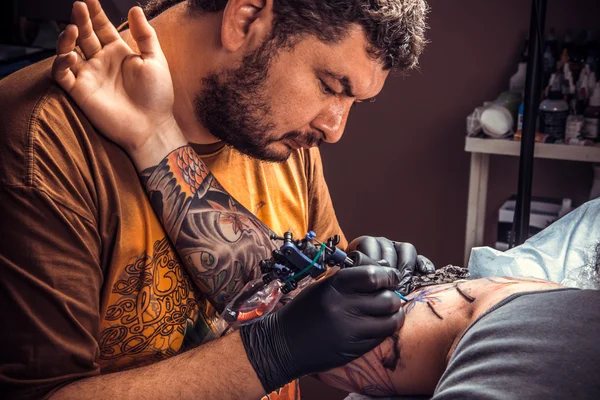 Professional tattoo artist working tattooing in studio