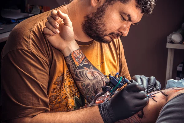 Master makes cool tattoo in tattoo studio.