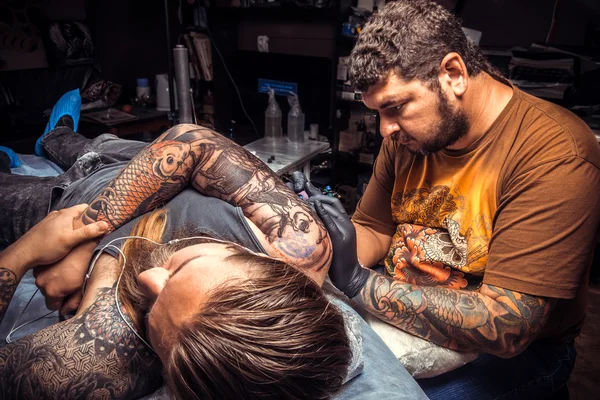 Man wearing gloves works in tattoo studio