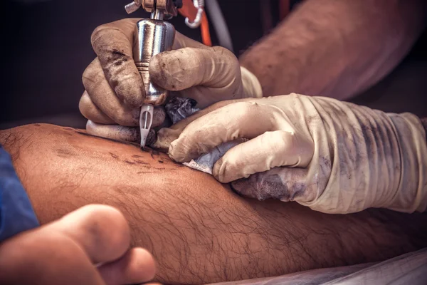 Tattooer working tattooing in tattoo studio.