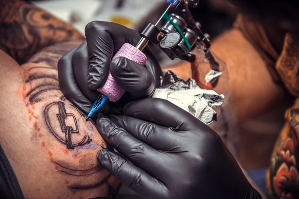 Professional tattooist makes cool tattoo in tattoo parlor