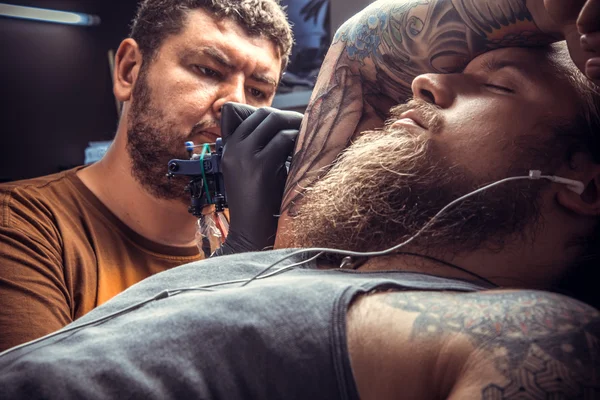 Tattoo master doing tattoo in tattoo parlor
