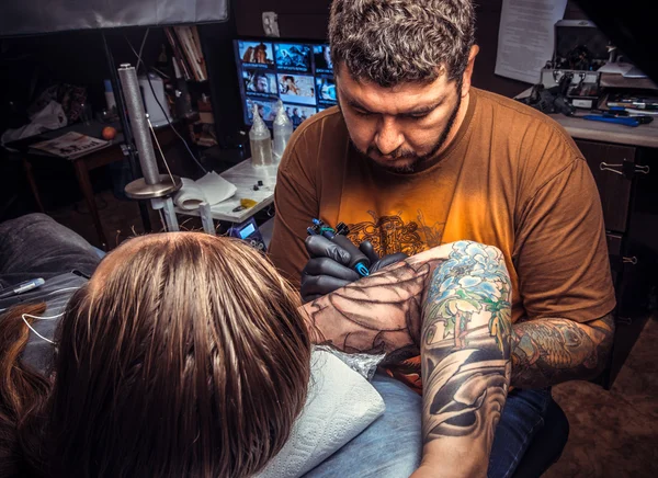 Tattoo specialist showing process of making a tattoo in studio