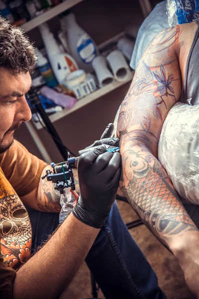 Professional tattoo artist doing tattoo in studio