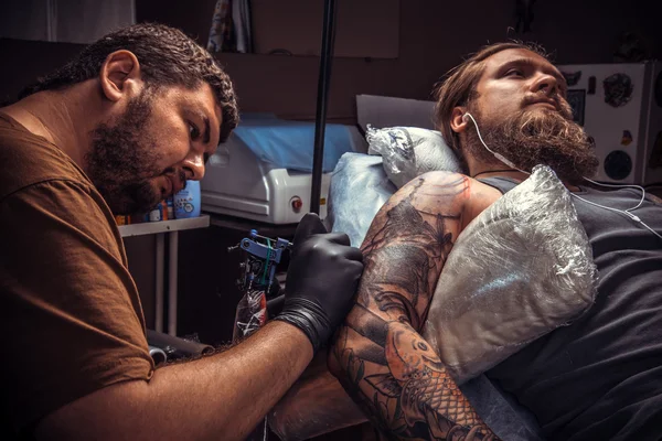 Professional tattooer showing process of making a tattoo in tatoo salon