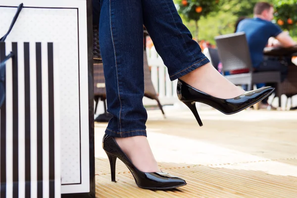 Attractive young female in sexy black high heels enjoying a break after successful shopping, detail shot, with copy space