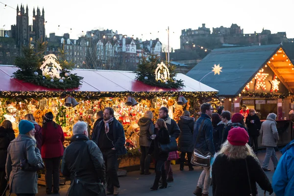 EDINBURGH, SCOTLAND, UK, December 08, 2014 - People walking among german christmas market stalls in Edinburgh, Scotland, UK, with Edinburgh castle in the background