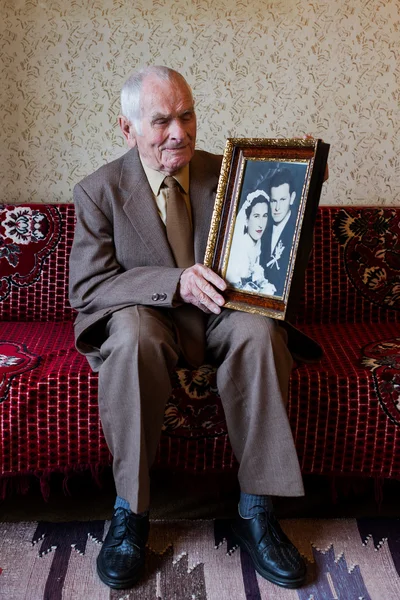 Handsome 80 plus year old senior man holding his wedding photograph. Love forever concept.