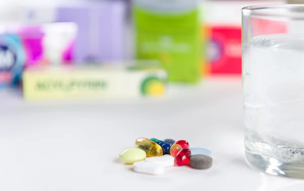 Colorful pills and glass of water, on white background