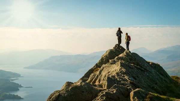 Two female hikers on top of the mountain enjoying valley view, Ben A\'an, Loch Katrine, Highlands, Scotland, UK