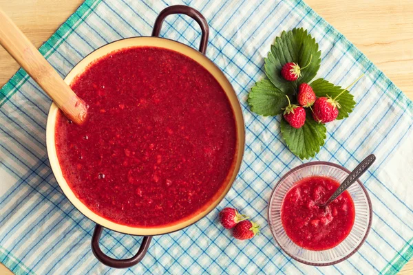 Homemade strawberry jam (marmelade) cooking. Large pot with hot jam and fresh strawberries