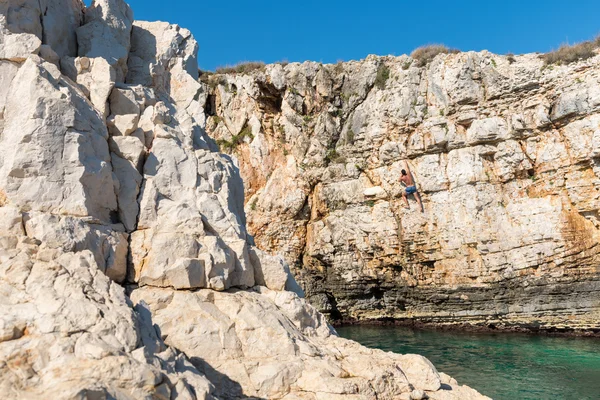 Young athletic man climbing sea cliffs without rope or harness in Croatia