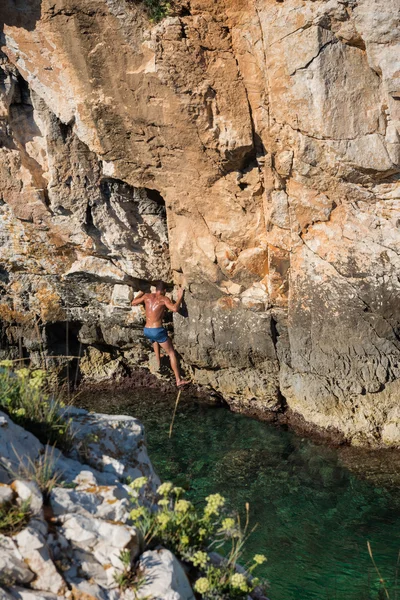 Young athletic man climbing sea cliffs without rope or harness in Croatia