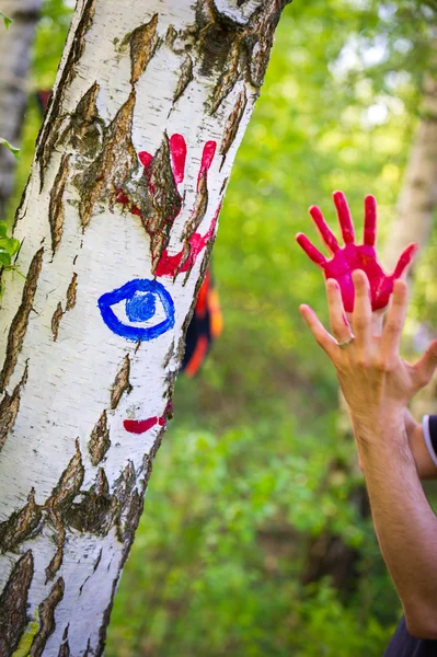 Person making colorful handprints on a birch tree