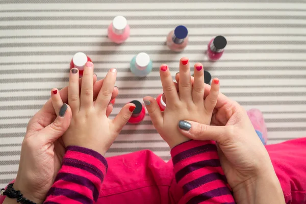 Mother and daughter having fun painting fingernails, family time concept, view from above