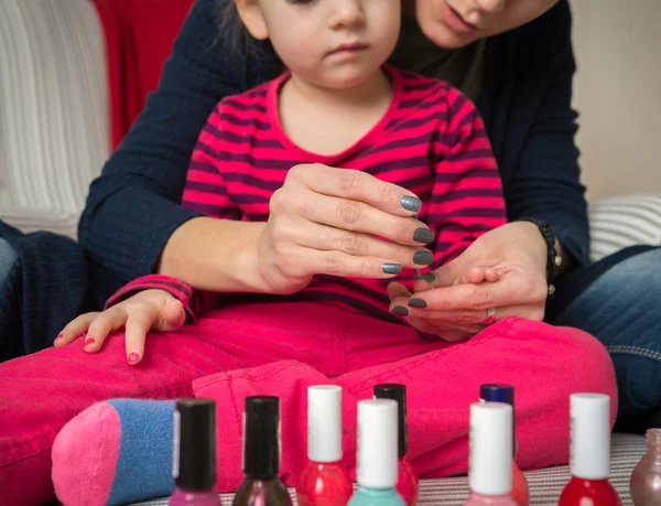 Mother and daughter having fun painting fingernails, family time concept