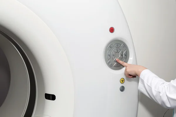 A hand of female doctor pushing control button on CT scanner