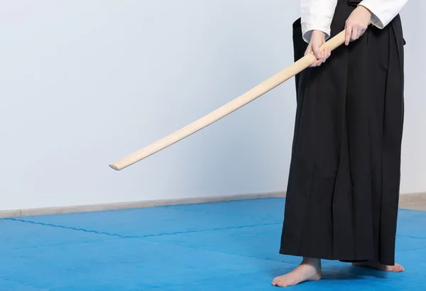A girl in black hakama standing in fighting pose with wooden sword