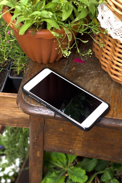Template. Phone on a wooden table, around the flowers in the baskets.