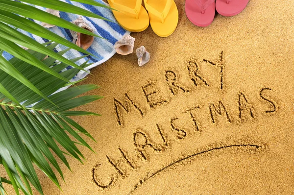 Merry Christmas message written in sand on a sunny tropical beach, Christmas holiday vacation concept