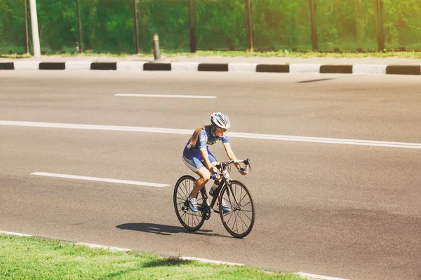 Female cyclist rides a racing bike on road