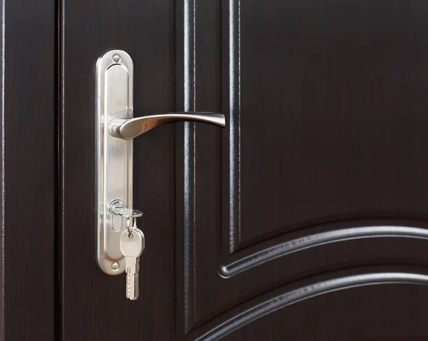 Closed dark brown wooden door handle with lock.