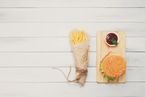Burger, chips and ketchup at white wood
