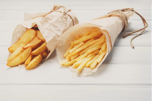Fries and potato wedges wrapped takeaway at wood