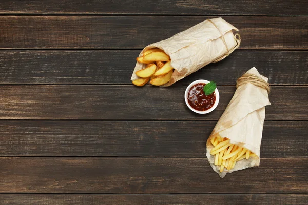Fries and potato wedges wrapped takeaway at wood