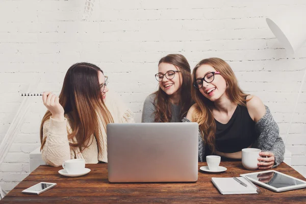 Portrait of three laughing girlfriends with laptop.