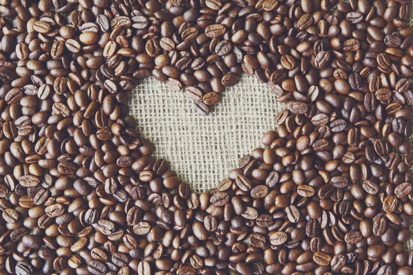 Coffee beans background with burlap heart frame