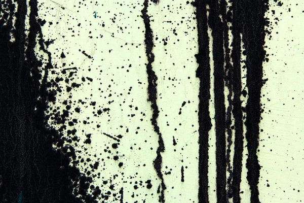 Green concrete wall with black paint drips, abstract background