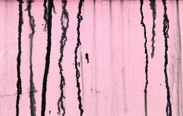 Pink concrete wall with black paint drips, abstract background