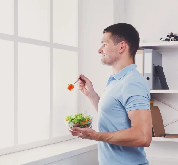 Man has healthy business lunch in modern office interior