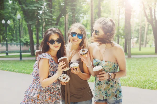 Three beautiful young boho chic stylish girls walking in park.