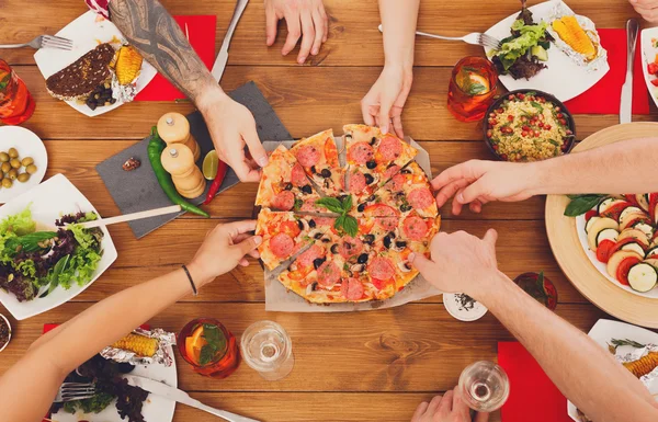 People eat pizza at festive table dinner party