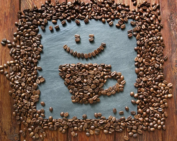 Smiley face from coffee beans at stone background