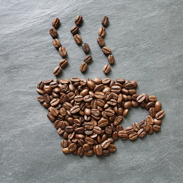 Cup from coffee beans at stone background